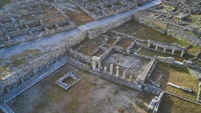 Drone shot, first morning light, Ancient ruins with columns and wall remains in an archaeological