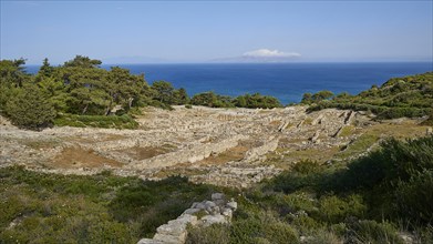 Extensive ruins of an ancient site on a green hill with the sea in the background, Kamiros,