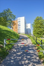 Walkway with barriers to a high-rise building in a residential area in the summer with lush green