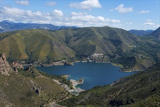 Large blue lake, surrounded by green mountains and hills, under a cloudy sky, reservoir, Embalse de