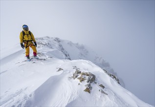 Ski tourers in a snowy mountain landscape, at the summit of the Wildhorn, cloudy mood, high tour,