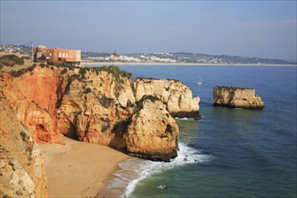 Praia do Pinhao, Lagos, Algarve, Portugal, cliff with orange-coloured rocks, adjacent sandy beach