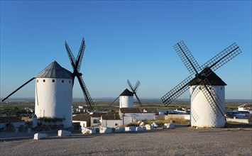 White painted windmills against a blue sky in a rural landscape, illuminated by sunlight,