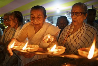 Elderly women of Pramod Talukdar Memorial Old Age Home light Diya oil lamps as they celebrate