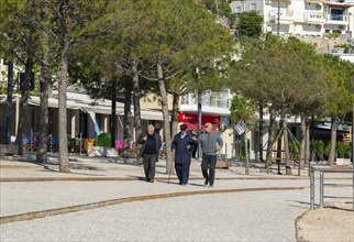 Old men walking on seafront promenade at seaside town of Himare, Albanian Riviera, Albania, Europe