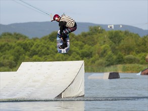 Man with wakeboard, jump over obstacle, water sports in lake, water ski and wakepark, Stráž pod