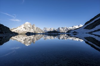 Mountaineer, silhouette in front of mountain landscape in the evening light, water reflection in