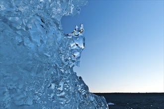 Light reflections in a stranded piece of iceberg after sunset, blue mood, Diamond Beach,