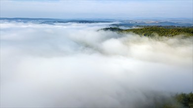 Dense early morning fog low lying clouds lie over valleys of low mountain ranges, Germany, Europe