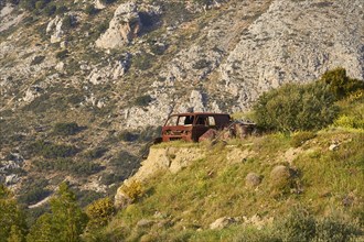 Abandoned rusted car on a rocky meadow in front of majestic mountains, Vehicle wreck, Crete, Greek