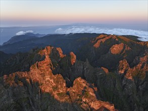 Aerial drone view of Pico do Arieiro and mountains over clouds on sunset. Above Pico Ruivo, Madeira