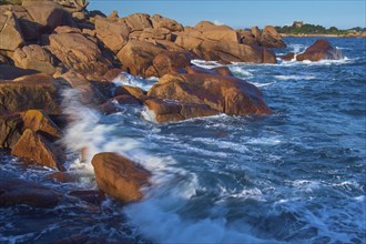 Large rocks on the Granit Rose coast, lapped by the dynamic waves of the blue sea, Ploumanach, Cote