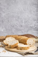 Sliced bread with different kinds of fresh baked bread on a gray concrete background. side view,