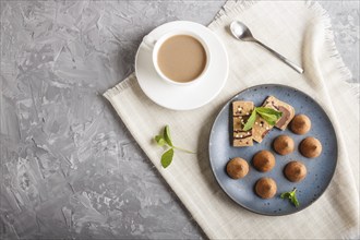 Chocolate truffle on blue ceramic plate and a cup of coffee on gray concrete background. top view,