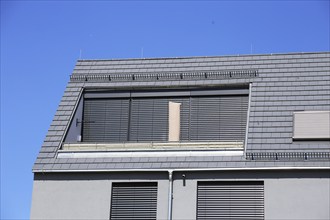 Modern tiled roof with large dormer window and urban-style blinds