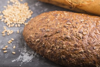 Fresh baked bread with grains on a black concrete background. side view, selective focus, close up