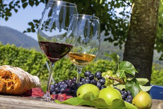 Symbolic image of the grape grape harvest: Ripe grapes decorated with wine glasses on a wooden