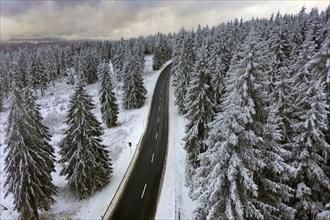 Aerial view, road leads through a snow-covered forest area near Sankt Andreasberg, 14 December 2019