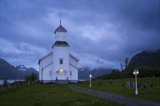 The white church of Gimsoy (Gimsoysand church) by the sea. A path leads to the church. The church