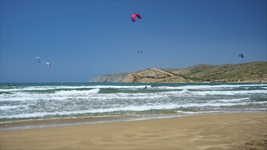 Several kitesurfers on the waves, with a beach and mountains in the background, surfers paradise,