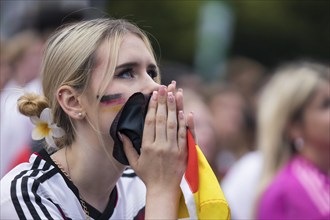 A woman watches the football match in the fan zone at the Brandenburg Tor during the quarter-final