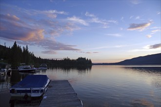 A calm lake at sunset, a jetty with boats and idyllic nature in the background, St. George, British