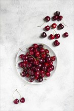 Red cherry, cherry berry, scattered on a plate, top view, no people