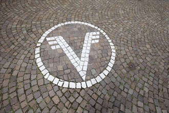 White floor mosaic with Volksbank emblem, paving stones, floor, logo, trademark, bank, sign, V,