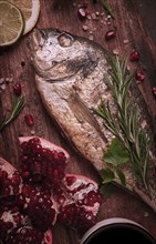 Fried dorado fish, with spices and herbs, on a wooden board, pomegranate sauce, close-up, no people