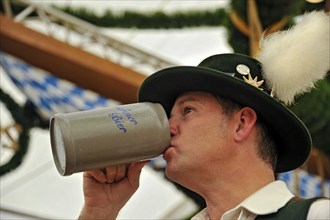 Man in traditional Bavarian traditional costume drinking beer from a beer mug, beer mug, old