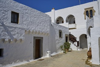 Courtyard of a historic building with white walls and arches under a blue sky, Inside the