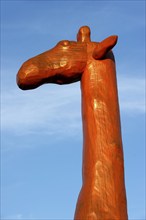 Head and neck of a giraffe made of red painted tree trunks, wooden sculpture by Günter Schumann,