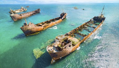 Abandoned, rusty shipwrecks in clear blue water off a coast under a blue sky, symbol photo, AI