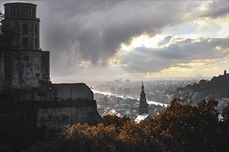 Romantic view of the city of Heidelberg with river and castle under a dramatic sky and falling