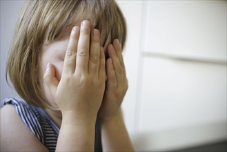 Symbolic photo on the subject of fear in children (posed scene) . A little girl holds her hands in