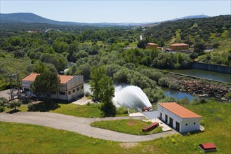 Building in a green setting with a large stream of water flowing from a reservoir, Embalse de