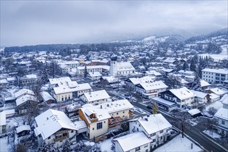 Snow-covered town with mountains in the background and thick clouds in the sky, Bad Feilnbach