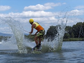 Sporty man with jump with wakeboard, water sports, water skiing and wake park