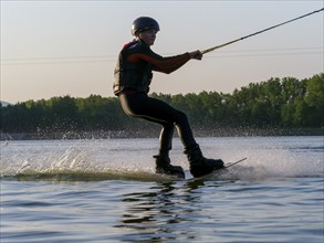 Young man with wakeboard in lake, water sports, water skiing in wakepark