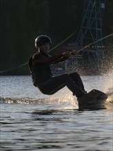 Young man with wakeboard in lake, fast ride, water sports, water skiing in wakepark