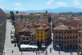 Lively old town with bustling streets, people and cafés against a mountain backdrop, Segovia,