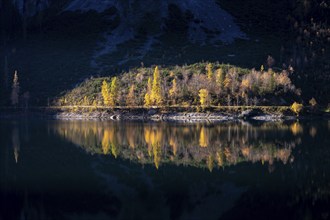 The Vordere Gosausee in autumn. Part of the path around the lake lies in the sun, the scene is