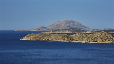 Close to a larger island in the blue sea, surrounded by blue sky and natural landscape, Makri