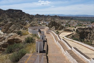 Panoramic view of a mountainous landscape with winding paths and a wide horizon under a summer sky,