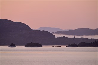 Atmospheric landscape scene with pastel-coloured sky, calm sea and silhouetted islands in the