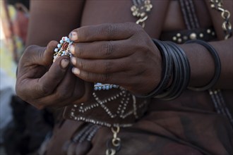 Hands of a Himba woman making bracelets, near Opuwo, Kaokoveld, Kunene, Namibia, Africa