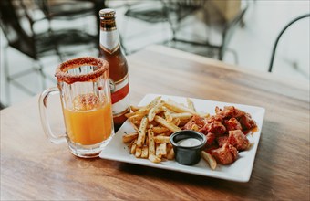 Spicy chicken wings with french fries and beer served on wooden table with copy space