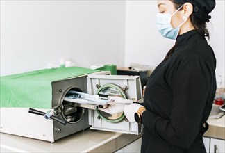 Dentist with a dental sterilizer, A dentist sterilizing his tools, A dentist with a dental