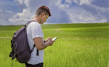 Man calling by cell phone, young man in the field calling by cell phone, young backpacker with cell