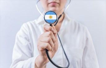 Female doctor holding stethoscope with Argentina flag. Argentine Health and Care concept